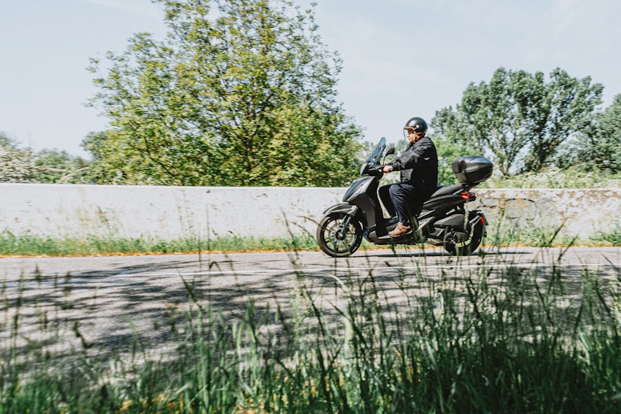 Rider on a motor scooter along a scenic countryside road